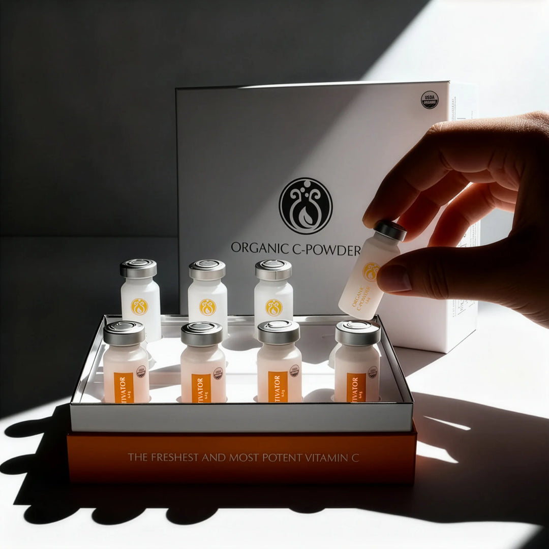 Hand holding a vitamin C powder bottle with a display of similar bottles and a branded box in the background.